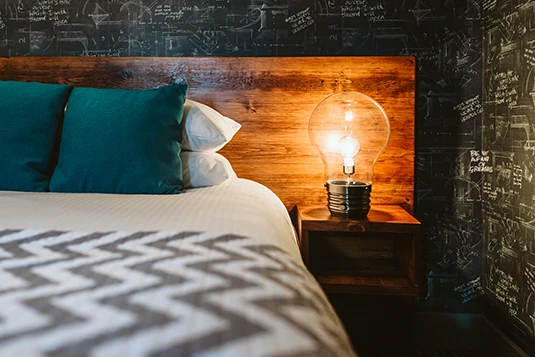 Room 6: E=MC Squared, queen bed with industrial/vintage nightstand decor